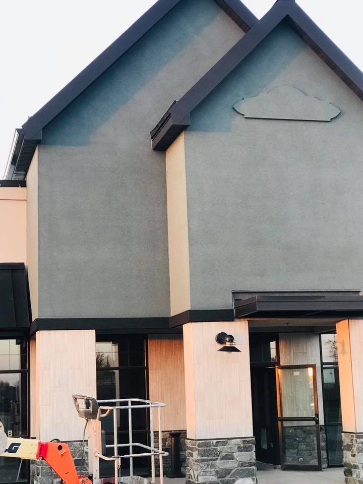 Commercial stucco exterior repaint with two-tone gable, lift in foreground, RPS Painting, Sioux Falls SD.